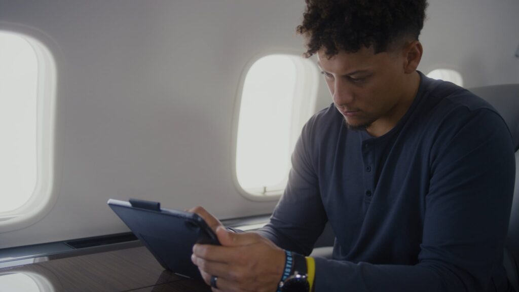 Athlete seated on a private jet uses a tablet during flight.