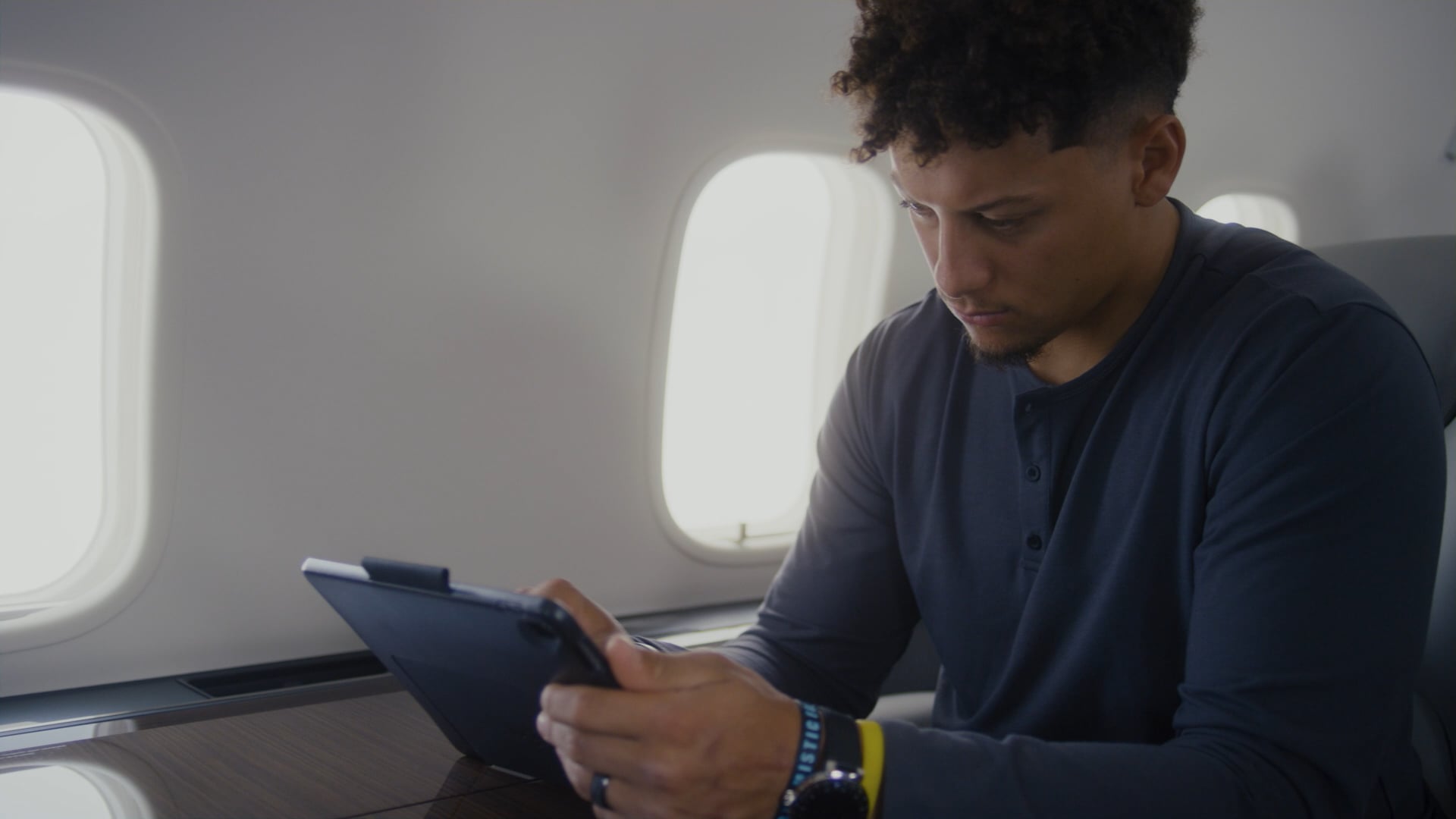 Athlete seated on a private jet uses a tablet during flight.