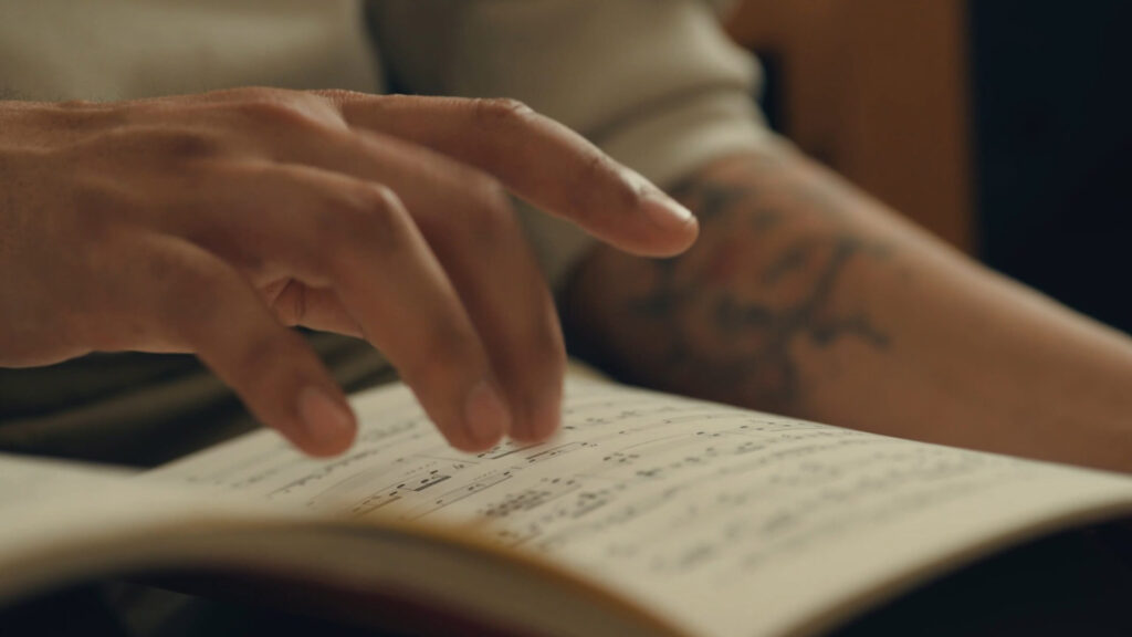Close-up of a student’s hand turning sheet music during music study or performance practice.