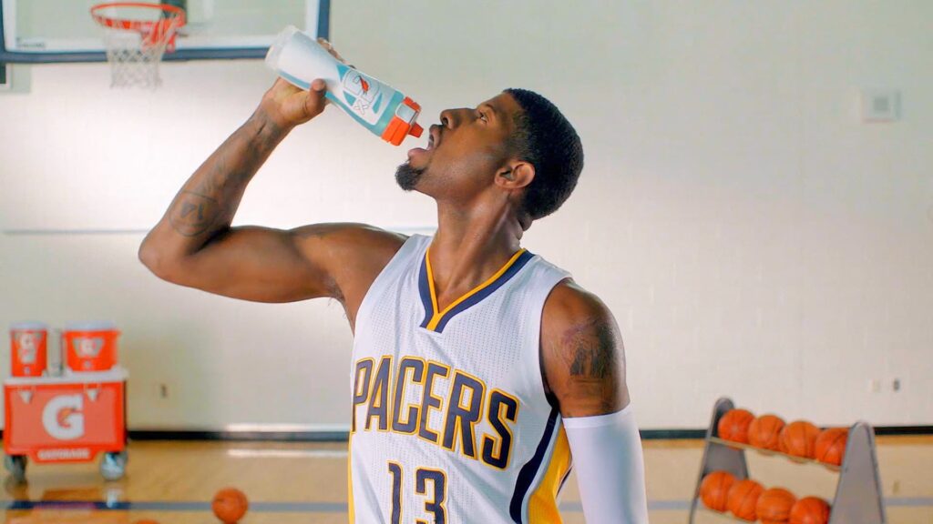 Indiana Pacers player drinks from a Gatorade bottle during basketball practice on an indoor court.