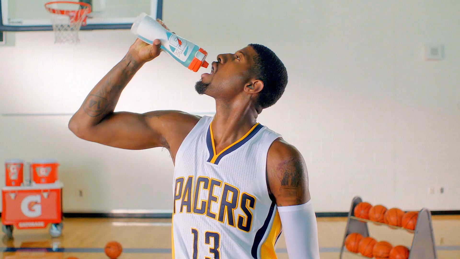 Indiana Pacers player drinks from a Gatorade bottle during basketball practice on an indoor court.