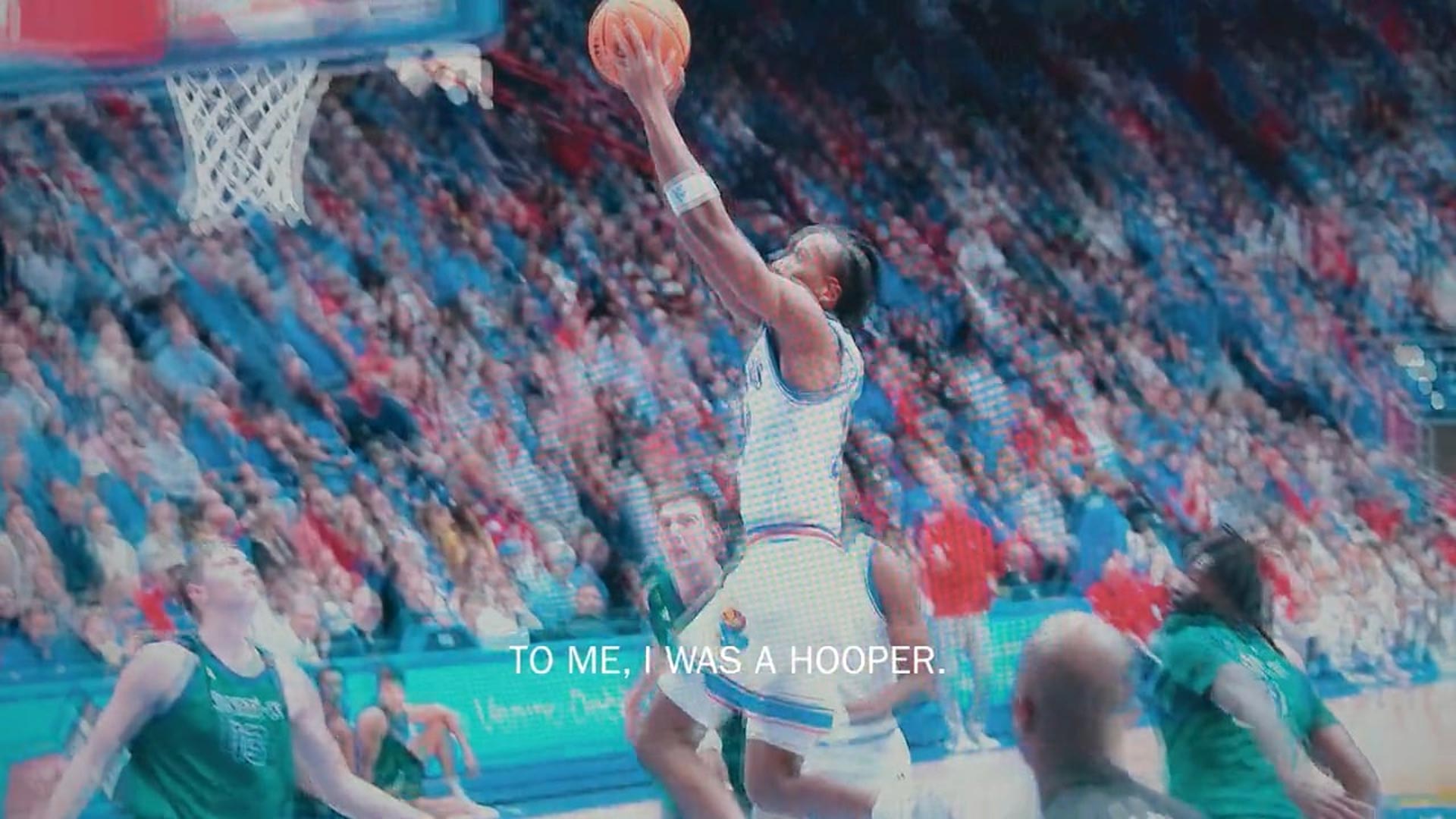 Basketball player drives for a layup in a packed arena during a college basketball game.
