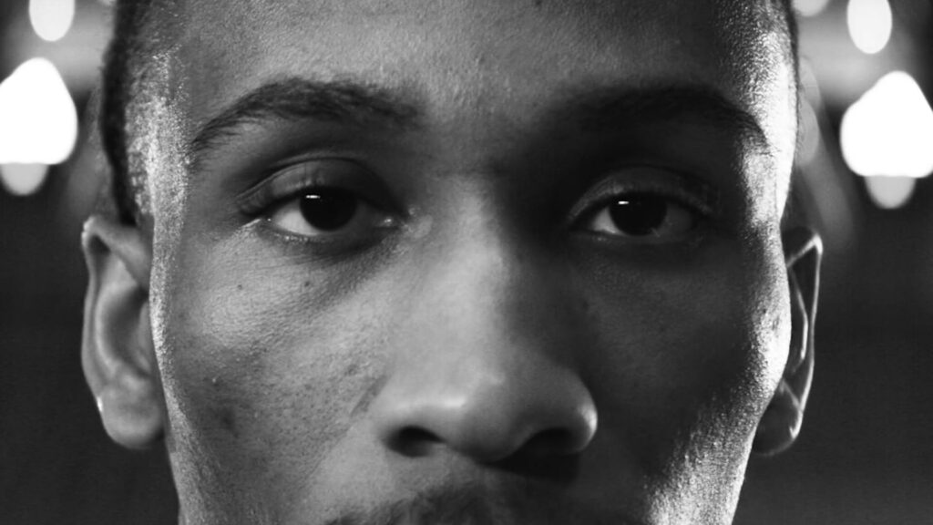 Black-and-white close-up portrait of a focused basketball player with dramatic lighting.